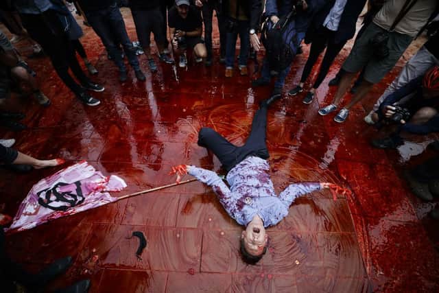 A climate activist from the Extinction Rebellion group lies down in fake blood smeared on the floor of Paternoster Square next to St Paul’s Cathedral in the City of London. Credit: TOLGA AKMEN/AFP via Getty Images