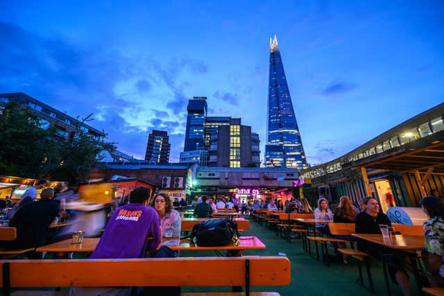 Vinegar Yard is an open air bar near London Bridge. Customers enjoy a drink at the outdoor seating just after sunset. The Shard and Guy’s Hospital are behind. Credit: Shutterstock