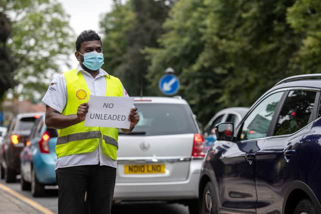 A Shell garage employee holds a sign on the side of the road informing a queue of traffic that they do not have unleaded petrol on September 25, 2021 in Blackheath, London, United Kingdom. Credit: Chris J Ratcliffe/Getty Images