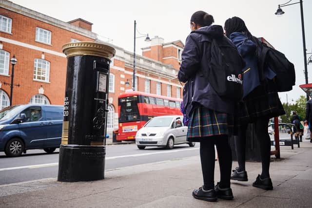 Two schoolgirls stop to look at one of four postboxes painted black (Photo by Leon Neal/Getty Images)