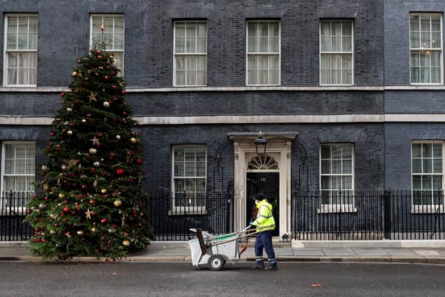 A City of Westminster worker cleans the street in front of 10 Downing Street, the official residence of Prime Minister, Boris Johnson, in central London on December 8, 2021.