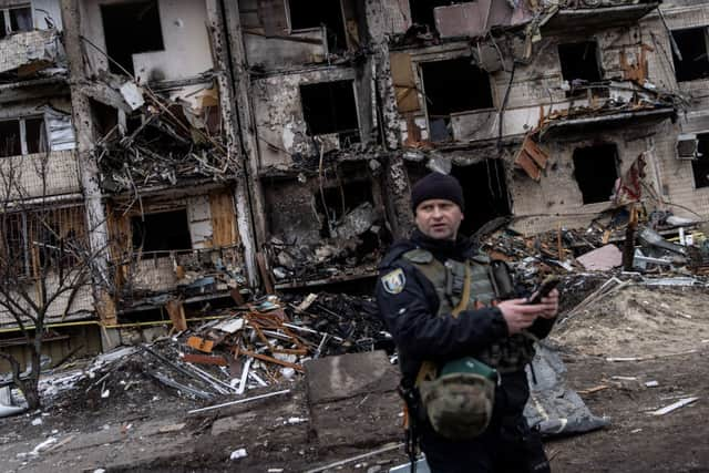 A Ukrainian police officer stands in front of a damaged residential block hit by an early morning missile strike on February 25, 2022 in Kyiv, Ukraine. (Photo by Chris McGrath/Getty Images)