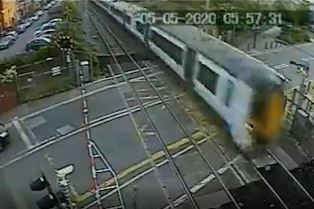 The Thameslink train just inches away from flattening the man jumping the crossing. Credit: SWNS