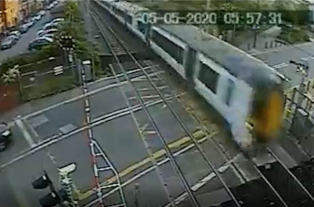The Thameslink train just inches away from flattening the man jumping the crossing. Credit: SWNS