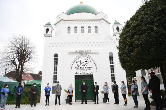 Health workers at the Fazl mosque vaccination centre take part in a minutes silence on the first anniversary  (Photo by Daniel LEAL / AFP) (Photo by DANIEL LEAL/AFP via Getty Images)