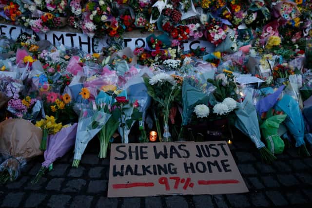 A sign saying “SHE WAS JUST WALKING HOME 97%” among the flowers and candles on Clapham Common where floral tributes have been placed for Sarah Everard on March 13, 2021 in London, England (Photo by Hollie Adams/Getty Images)