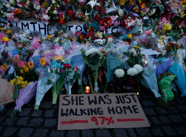 A sign saying “SHE WAS JUST WALKING HOME 97%” among the flowers and candles on Clapham Common where floral tributes have been placed for Sarah Everard on March 13, 2021 in London, England (Photo by Hollie Adams/Getty Images)