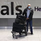A man wearing a mask stands at the international arrivals gate at Heathrow Terminal 5.