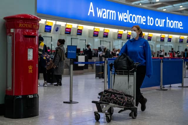 An airline passenger wearing a face mask pushes her bags past a post box at Heathrow Terminal 5. (Photo: Getty)