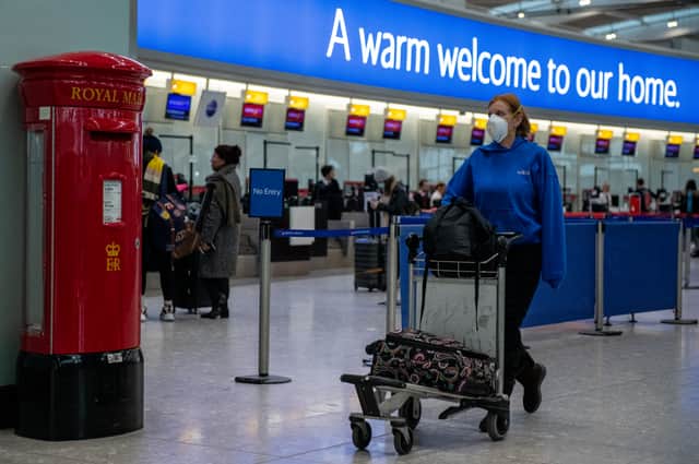An airline passenger wearing a face mask pushes her bags past a post box at Heathrow Terminal 5. (Photo: Getty)