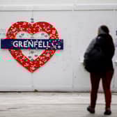A woman walks past a memorial near the burned-out shell of Grenfell Tower. Photo: Getty