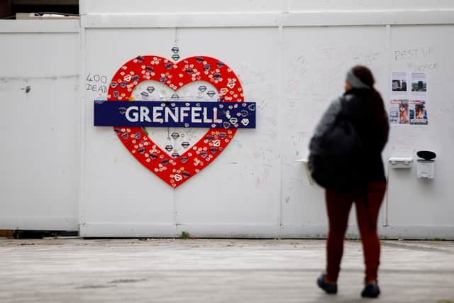 A woman walks past a memorial near the burned-out shell of Grenfell Tower. Photo: Getty