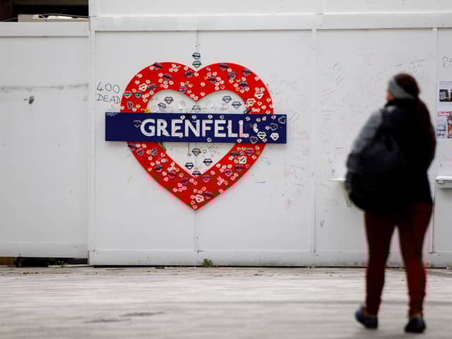 A woman walks past a memorial near the burned-out shell of Grenfell Tower. Photo: Getty