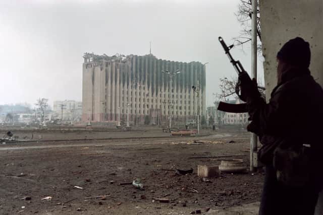 A Chechen fighter takes cover from sniper fire in front of the from the presidential palace destroyed by Russian artillery bombardments in Grozny on January 10, 1995. Credit: MICHAEL EVSTAFIEV/AFP via Getty Images