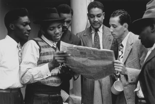 22nd June 1948:  Jamaicans reading a newspaper whilst on board the ex-troopship 'Empire Windrush' bound for Tilbury docks in Essex.  (Photo by Douglas Miller/Keystone/Getty Images)