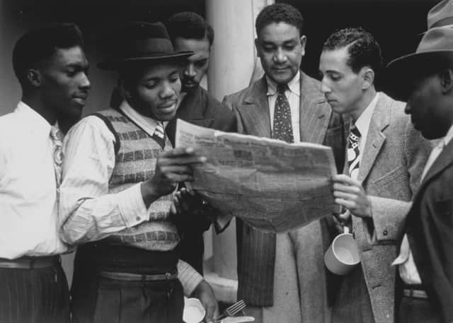 22nd June 1948:  Jamaicans reading a newspaper whilst on board the ex-troopship 'Empire Windrush' bound for Tilbury docks in Essex.  (Photo by Douglas Miller/Keystone/Getty Images)