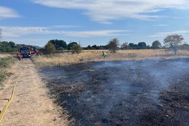 Firefighters work to dampen down the grass fire in Rammey Marsh Enfield. Credit: LFB
