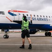 An Aircraft Turnaround Lead directs a British Airways plane on the runway at London City Airport