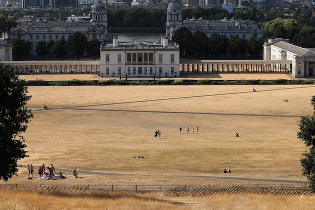 Visitors to Greenwich Park walk on the the dry brown grass in front of the National Maritime Museum in east London on July 23, 2018.