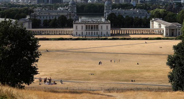 Visitors to Greenwich Park walk on the the dry brown grass in front of the National Maritime Museum in east London on July 23, 2018.