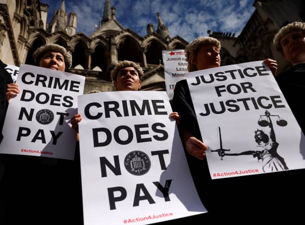 <p>Senior criminal lawyers hold placards outside the Royal Courts of Justice, as they go on strike in a dispute over pay. Photo: Getty</p>