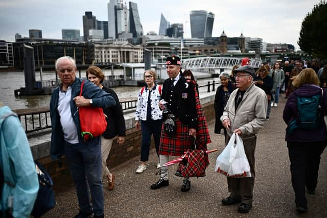 Members of the public stand in the queue, opposite the skyscrapers of the City of London. Photo: Getty