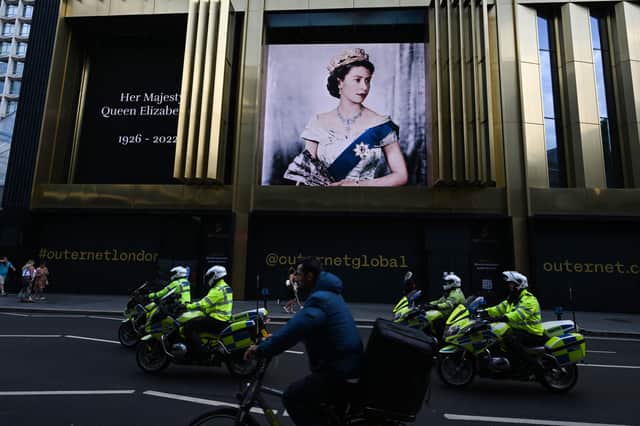 Police officers ride on motorcycles past a portrait of Britain’s Queen Elizabeth II. Photo: Getty