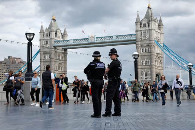 Two police officers stand as people walk in line along The Queens Walk near Tower Bridge. Photo: Getty