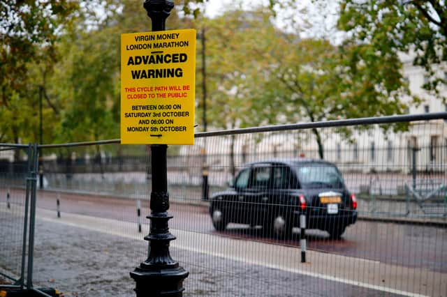 A taxi drives past an advance warning sign about road closure for the London Marathon