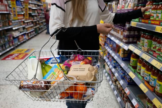 A woman holds a shopping basket of groceries. Last week, the UK Office for National Statistics reported an 6% average increase of food and drink prices year on year, but some staples, such as milk and pasta, had risen by more than 10%.