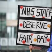 An NHS nurse in scrubs with a placard. Photo: Getty