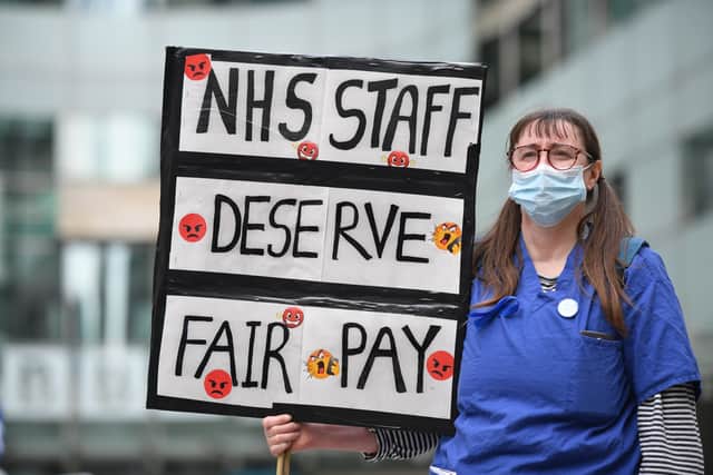 An NHS nurse in scrubs with a placard. Photo: Getty
