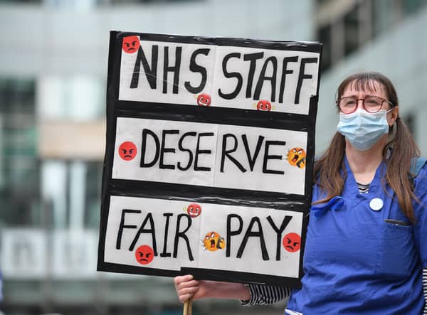 An NHS nurse in scrubs with a placard. Photo: Getty
