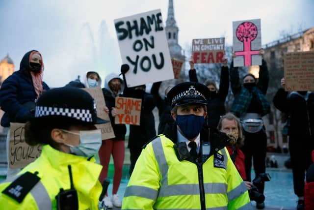 Police officers stand in front of members of the public holding up protest signs. Photo: Getty