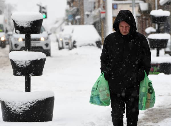 A pedestrian carries their shopping through the snow in Auchterarder, central Scotland, on February 18, 2022, as Storm Eunice brings high winds across the country.