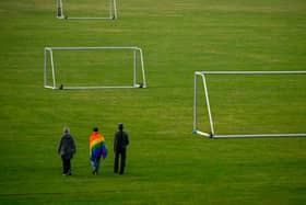 People walk with a Rainbow flag on a football field. Photo: Getty