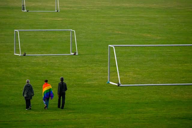 People walk with a Rainbow flag on a football field. Photo: Getty