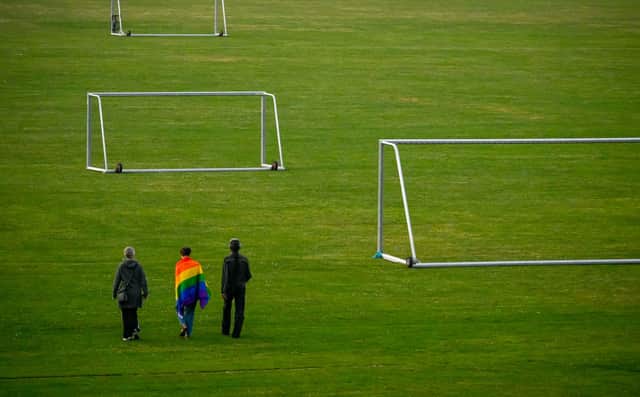 People walk with a Rainbow flag on a football field. Photo: Getty