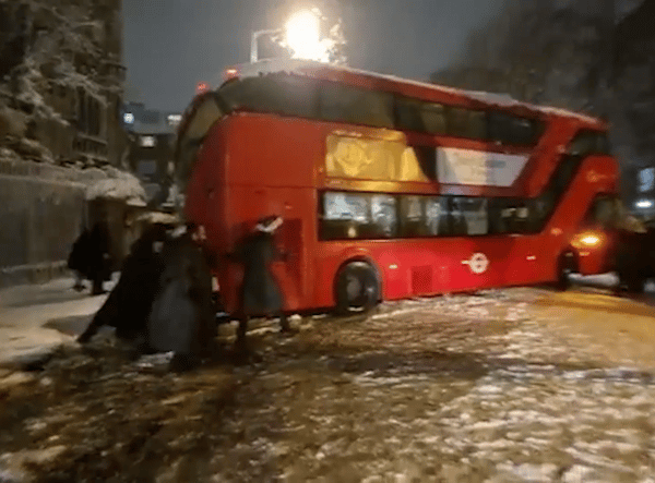 Londoners banded together to move a double-decker bus that got stuck during heavy snowfall. Photo: SWNS