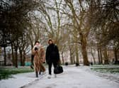 A couple walks in a park in the snow in central London.
