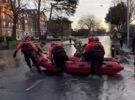 Residents are being ferried across roads after a major burst water pipe flooded the streets outside a London fire station. Credit: SWNS