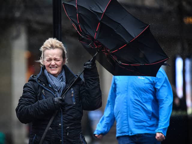 A woman battles to keep control of her umbrella as she walks through a rain shower in Glasgow.