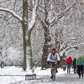 A person cycling through the snow in Kennington Park, London