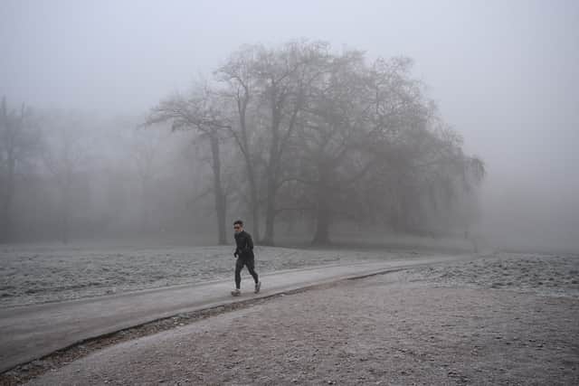 A jogger makes their way through fog on a frosty morning.