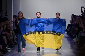 Ukrainian fashion designers Ksenia Schnaider, Ivan Frolov and Julie Paskal wave a Ukraine’s flag as they walk down the catwalk prior on the fifth day of London Fashion Week. (Picture: Justin Tallis/AFP via Getty Images)