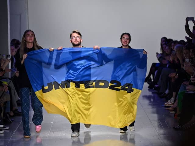 Ukrainian fashion designers Ksenia Schnaider, Ivan Frolov and Julie Paskal wave a Ukraine’s flag as they walk down the catwalk prior on the fifth day of London Fashion Week. (Picture: Justin Tallis/AFP via Getty Images)