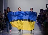 Ukrainian fashion designers Ksenia Schnaider, Ivan Frolov and Julie Paskal wave a Ukraine’s flag as they walk down the catwalk prior on the fifth day of London Fashion Week. (Picture: Justin Tallis/AFP via Getty Images)