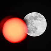 TOPSHOT - This picture taken on February 5, 2023 shows the full moon rising behind a red crossing light in Paris. (Photo by Stefano RELLANDINI / AFP) (Photo by STEFANO RELLANDINI/AFP via Getty Images)
