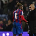 Pep Guardiola (R) shakes hands with Crystal Palace's Ivorian striker Wilfried Zaha (Photo by BEN STANSALL/AFP via Getty Images)