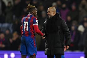 Pep Guardiola (R) shakes hands with Crystal Palace's Ivorian striker Wilfried Zaha (Photo by BEN STANSALL/AFP via Getty Images)